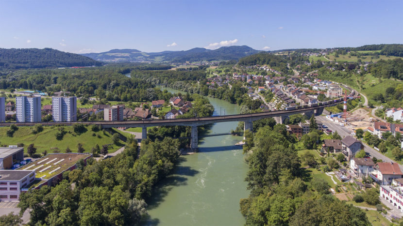 Blick stromaufwärts auf die Eisenbahnbrücke der Bözberglinie. Im Hintergrund ist das bewaldete Aaretal zwischen Schinznach und Brugg zu sehen